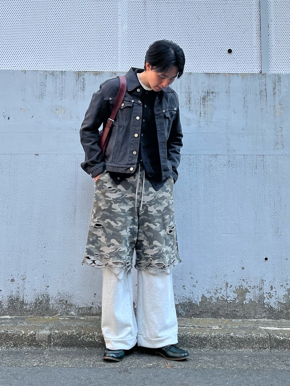 グレー系のスウェットパンツ、グリーン系のローファー、ブラック系のデニムジャケットを着用したメンズの春コーディネートの2枚目の写真