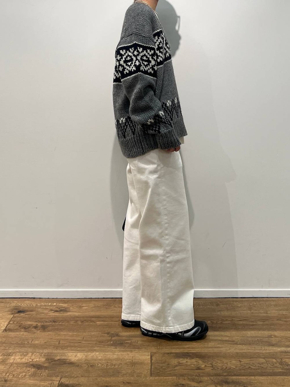 グレー系のニット/セーター、ブラック系のハンドバッグ、ホワイト系のデニムパンツを着用したレディースの秋コーディネートの2枚目の写真