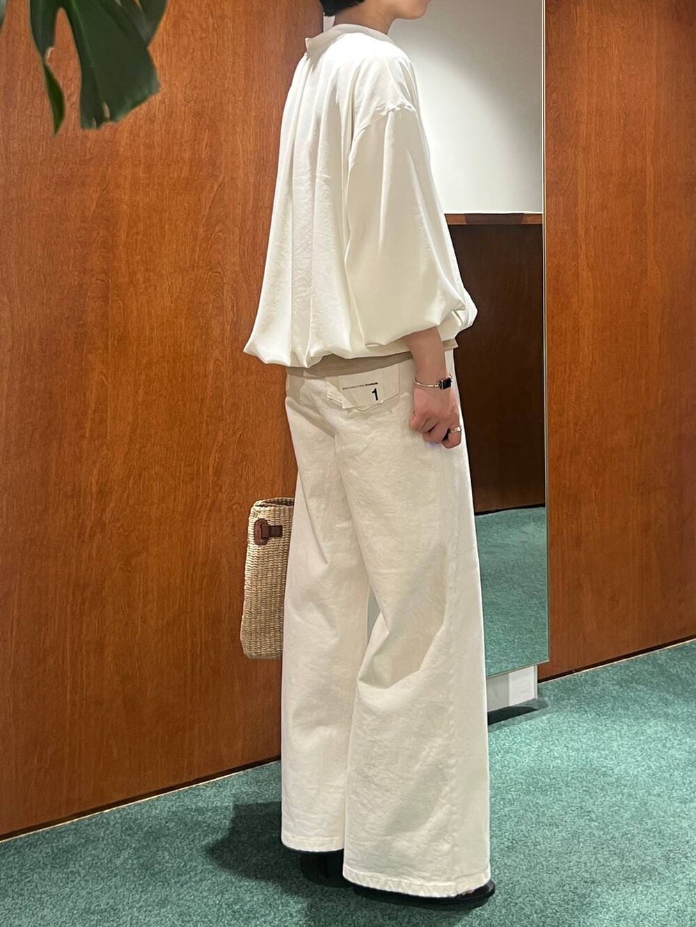 ホワイト系のデニムパンツ、ホワイト系のブルゾン、ベージュ系のキャミソールを着用したレディースの春コーディネートの2枚目の写真