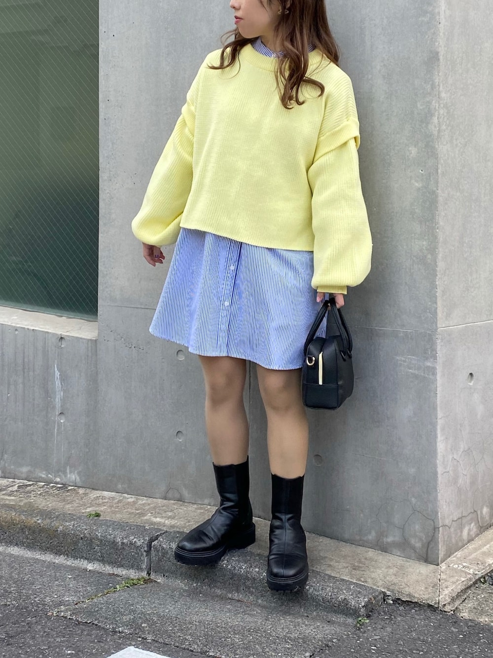 イエロー系のニット/セーター、ブルー系のシャツ/ブラウス、ブラック系のショルダーバッグを着用したレディースの春コーディネートの2枚目の写真