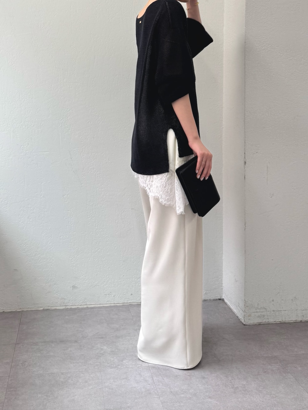 ブラック系のニット/セーター、ホワイト系のシャツ/ブラウス、ベージュ系のその他パンツを着用したレディースの春コーディネートの2枚目の写真