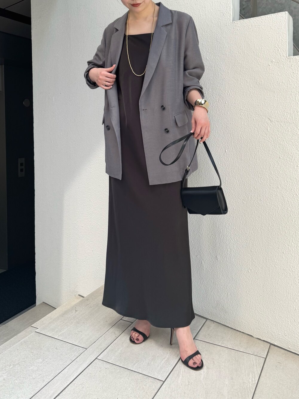 グレー系のワンピース、グレー系のベスト、ブラック系のトートバッグを着用したレディースの夏コーディネートの2枚目の写真