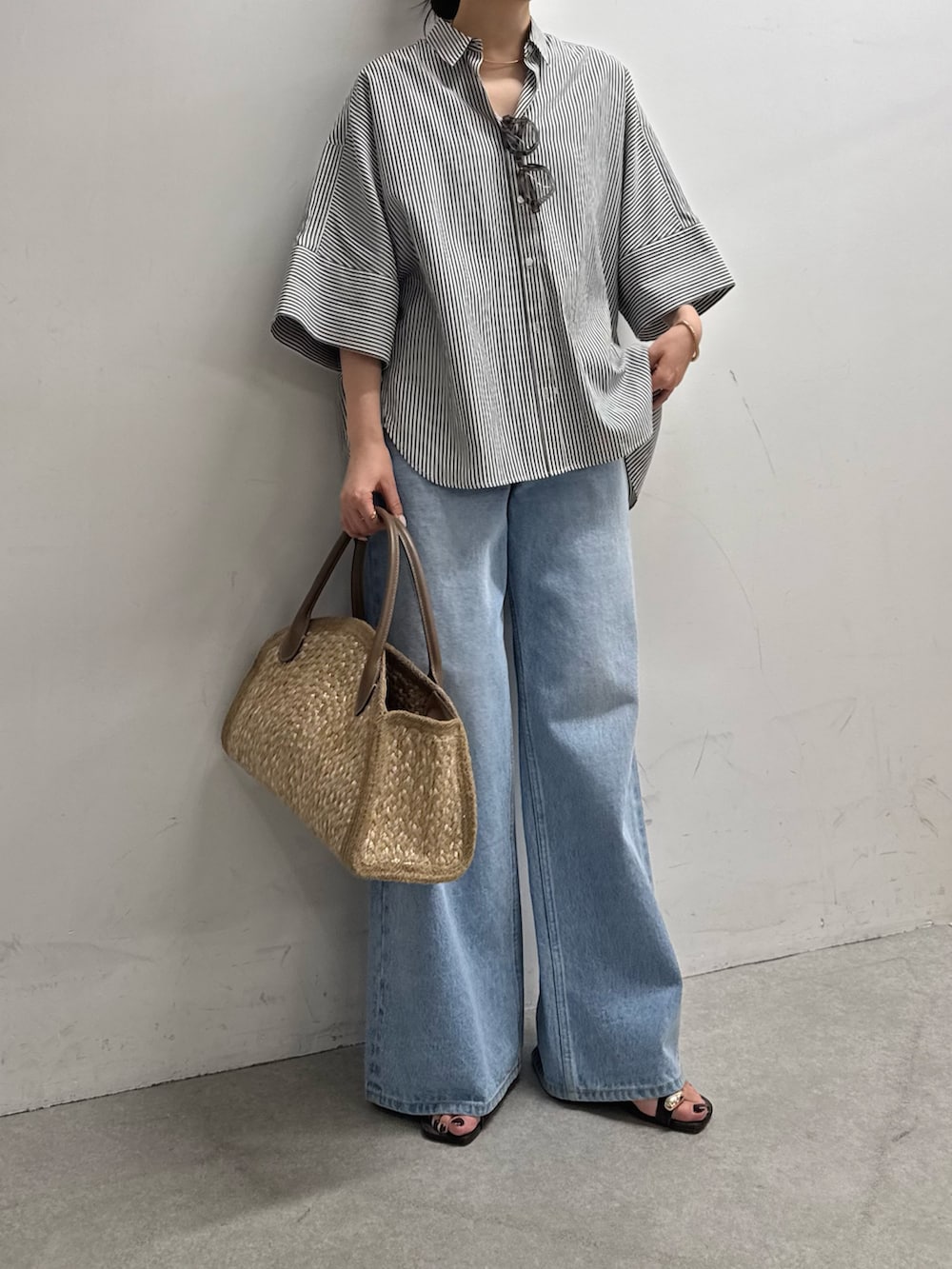 ブルー系のシャツ/ブラウス、ブルー系のデニムパンツ、ベージュ系のトートバッグを着用したレディースの春コーディネートの2枚目の写真