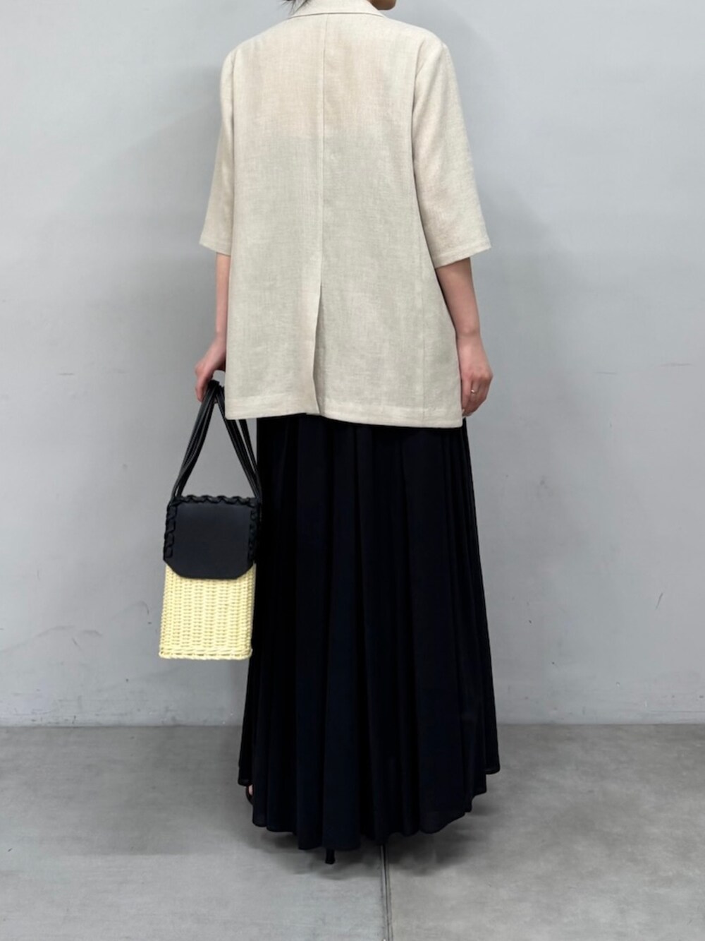 ベージュ系のテーラードジャケット、ブラック系のスカート、ブラック系のサンダルを着用したレディースの春コーディネートの4枚目の写真