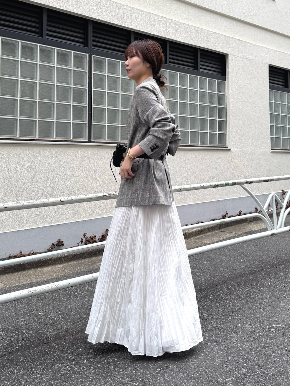 ブラック系のショルダーバッグ、ブラック系のその他アウター、ホワイト系のスカートを着用したレディースの冬コーディネートの2枚目の写真