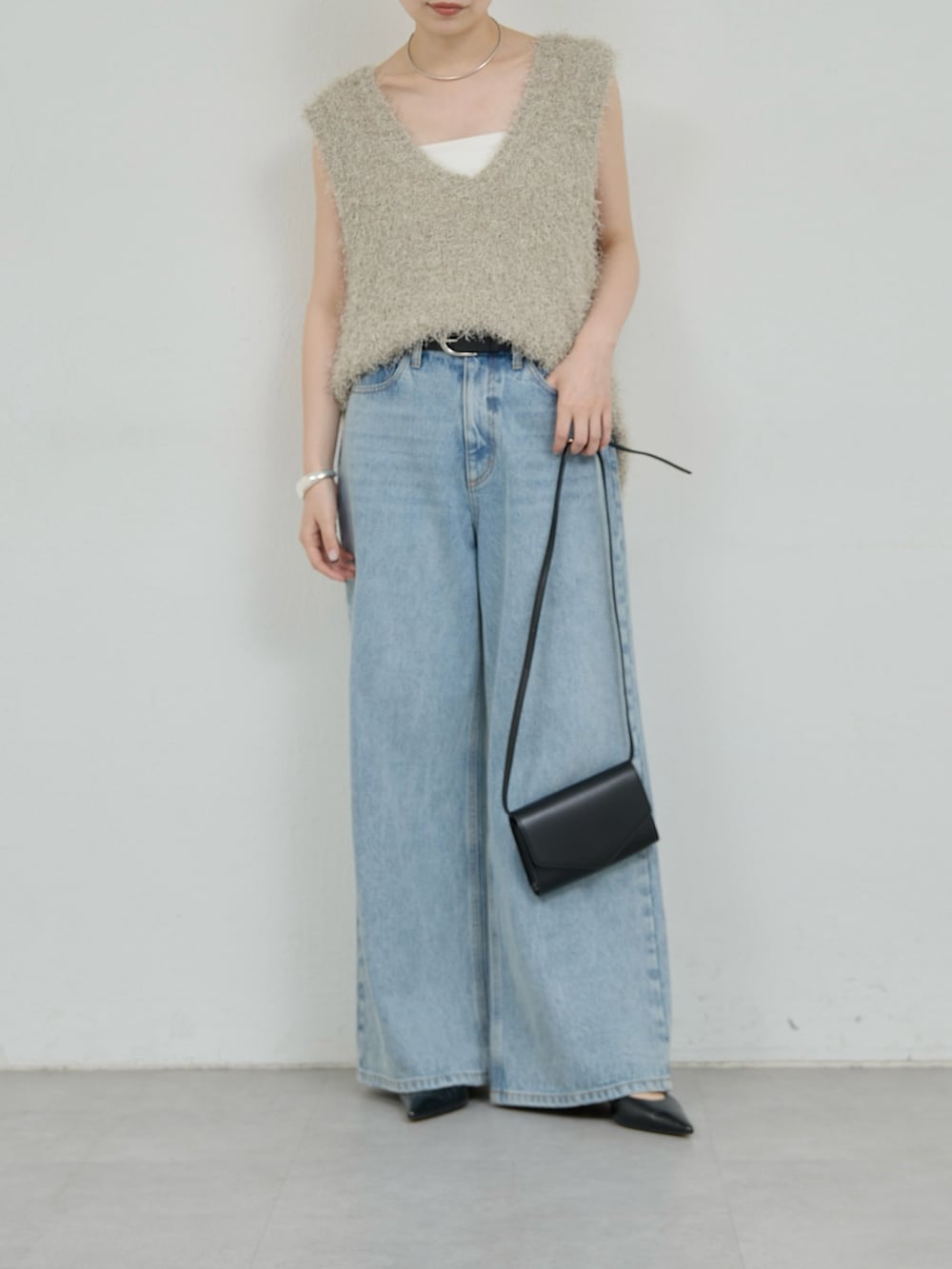 グレー系のニット/セーター、ブルー系のデニムパンツ、ブラック系のトートバッグを着用したレディースの夏コーディネートの2枚目の写真