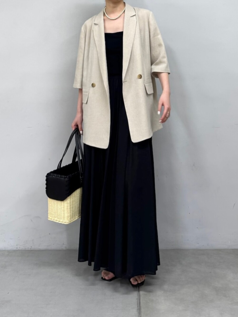 ベージュ系のテーラードジャケット、ブラック系のスカート、ブラック系のサンダルを着用したレディースの春コーディネートの2枚目の写真