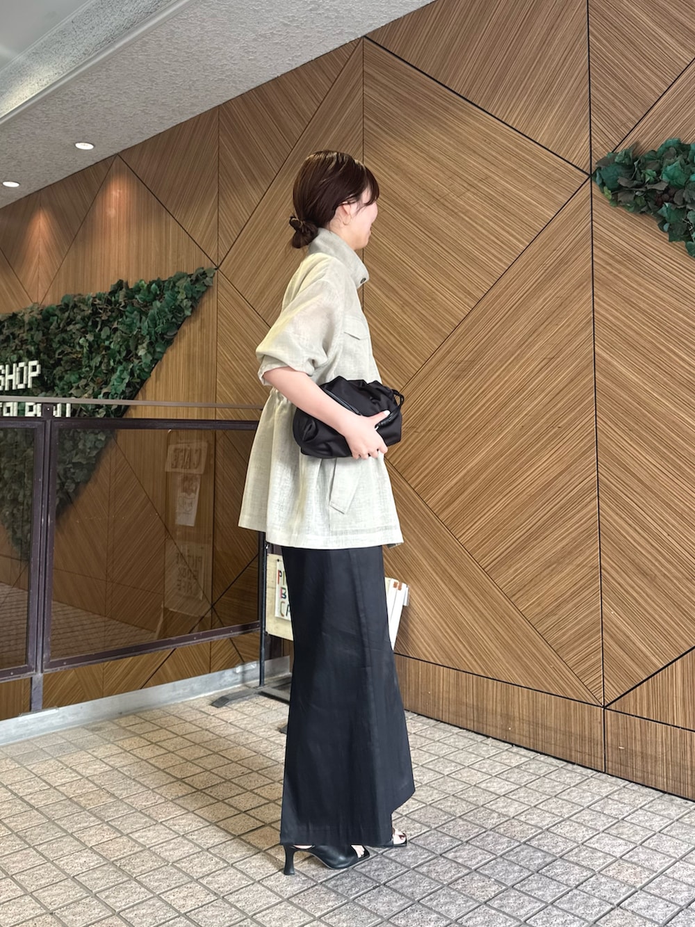 ブラック系のスカート、ブラック系のサンダル、グリーン系のベストを着用したレディースの春コーディネートの2枚目の写真