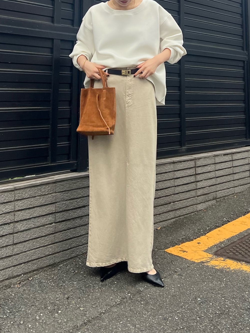 ベージュ系のスカート、ホワイト系のTシャツ/カットソー、ブラック系のベルトを着用したレディースの春コーディネートの2枚目の写真