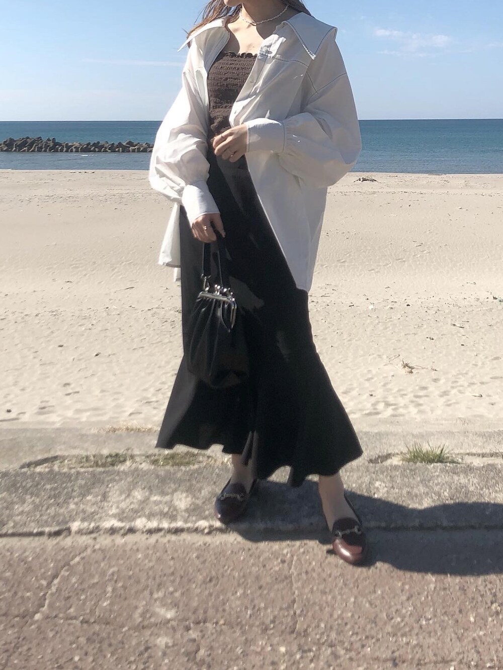 ホワイト系のシャツ/ブラウス、ブラウン系のキャミソール、ブラック系のスカートを着用したレディースの春コーディネートの2枚目の写真