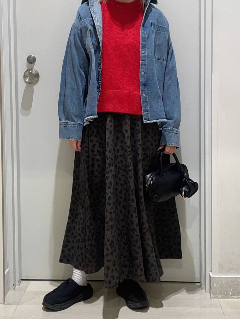 レッド系のニット/セーター、ブラック系のハンドバッグ、ブラック系のその他シューズを着用したレディースの冬コーディネートの2枚目の写真