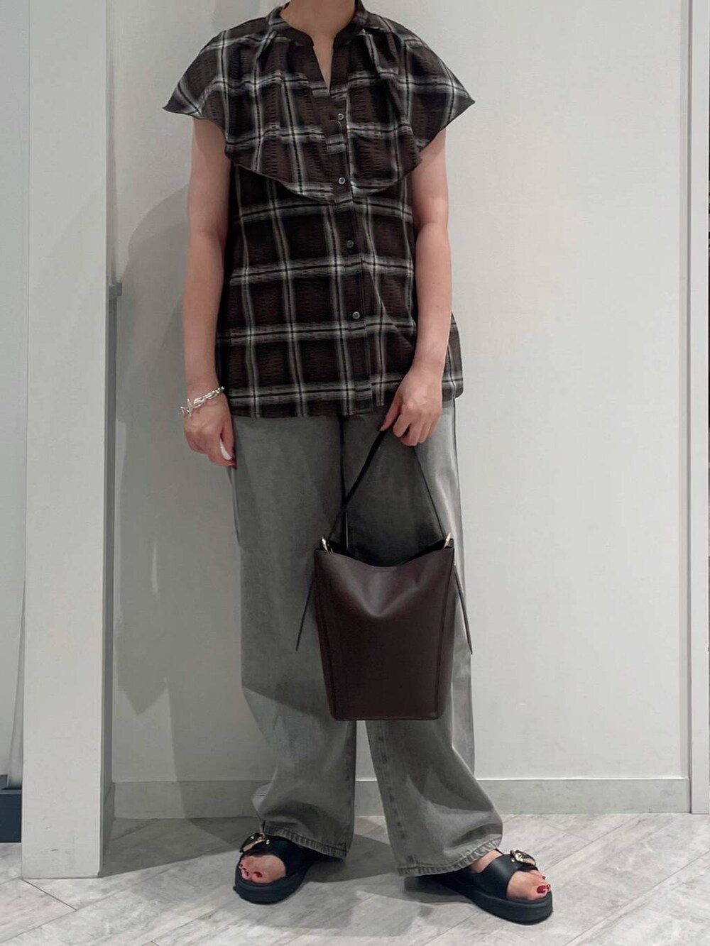 グレー系のデニムパンツ、ブラウン系のショルダーバッグ、ブラック系のタンクトップを着用したレディースの夏コーディネートの2枚目の写真