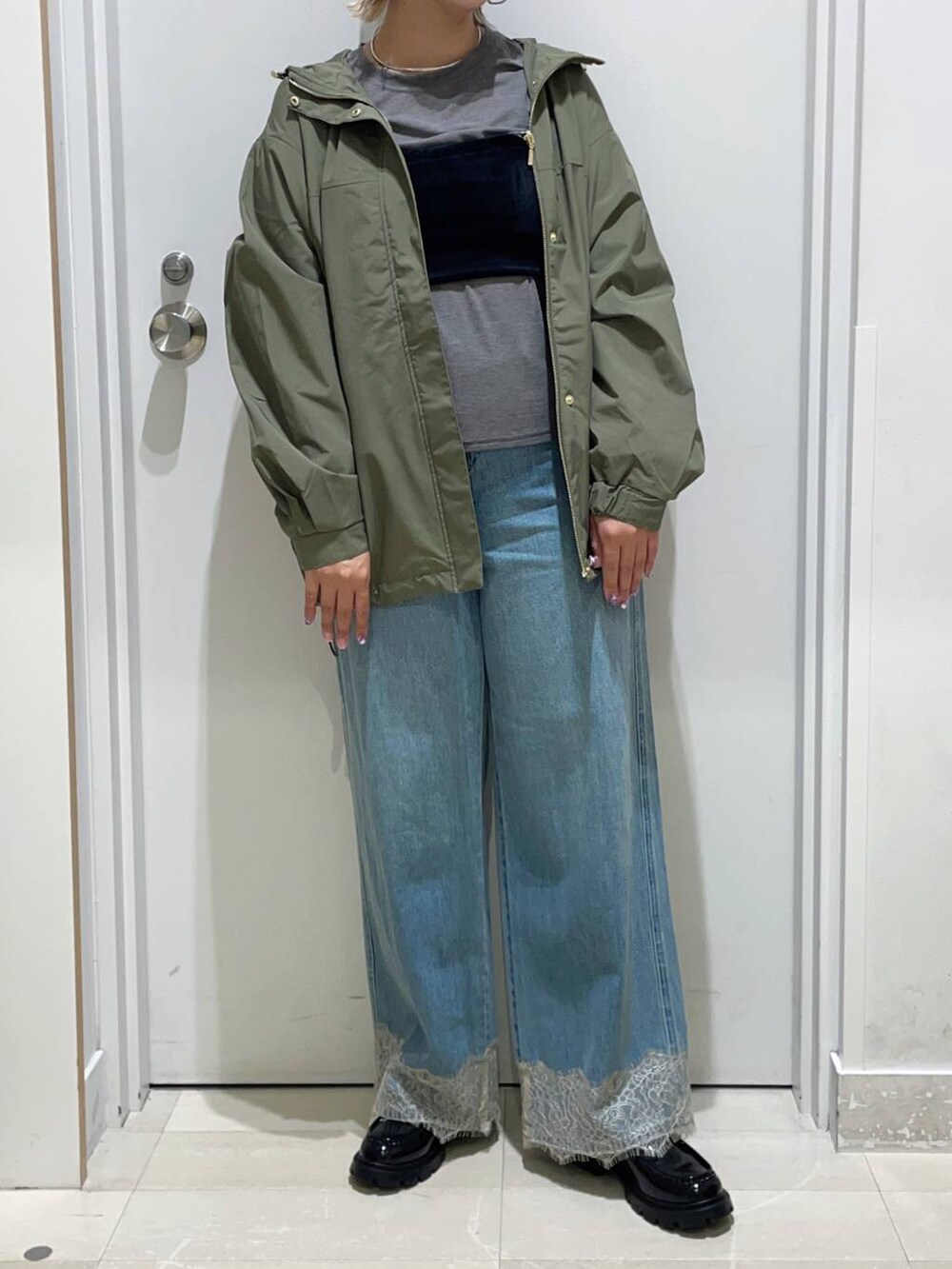 グレー系のTシャツ/カットソー、グリーン系のマウンテンパーカー、ブルー系のデニムパンツを着用したレディースの秋コーディネートの2枚目の写真