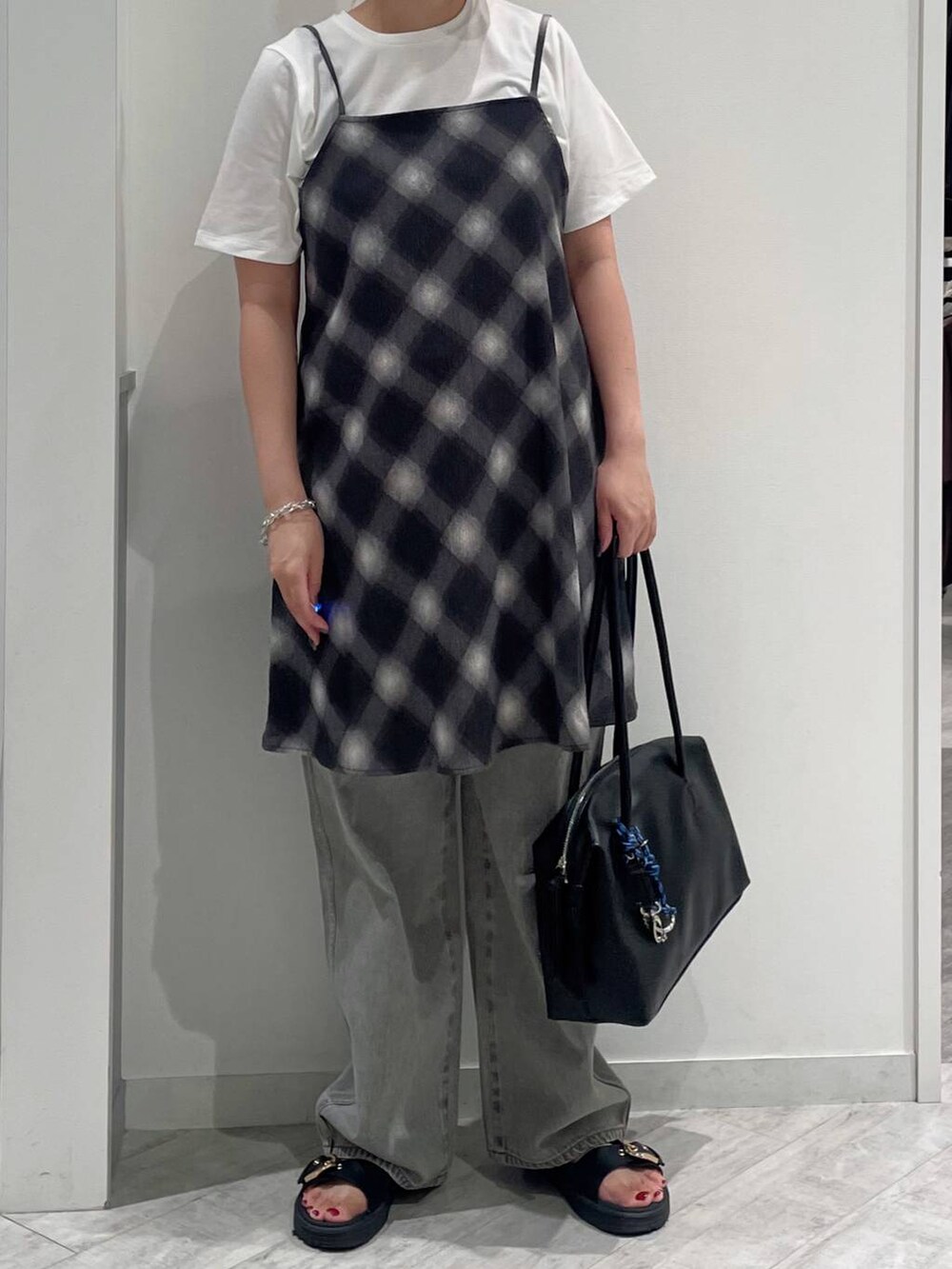 グレー系のデニムパンツ、ホワイト系のTシャツ/カットソー、ブラック系のボストンバッグを着用したレディースの夏コーディネートの2枚目の写真