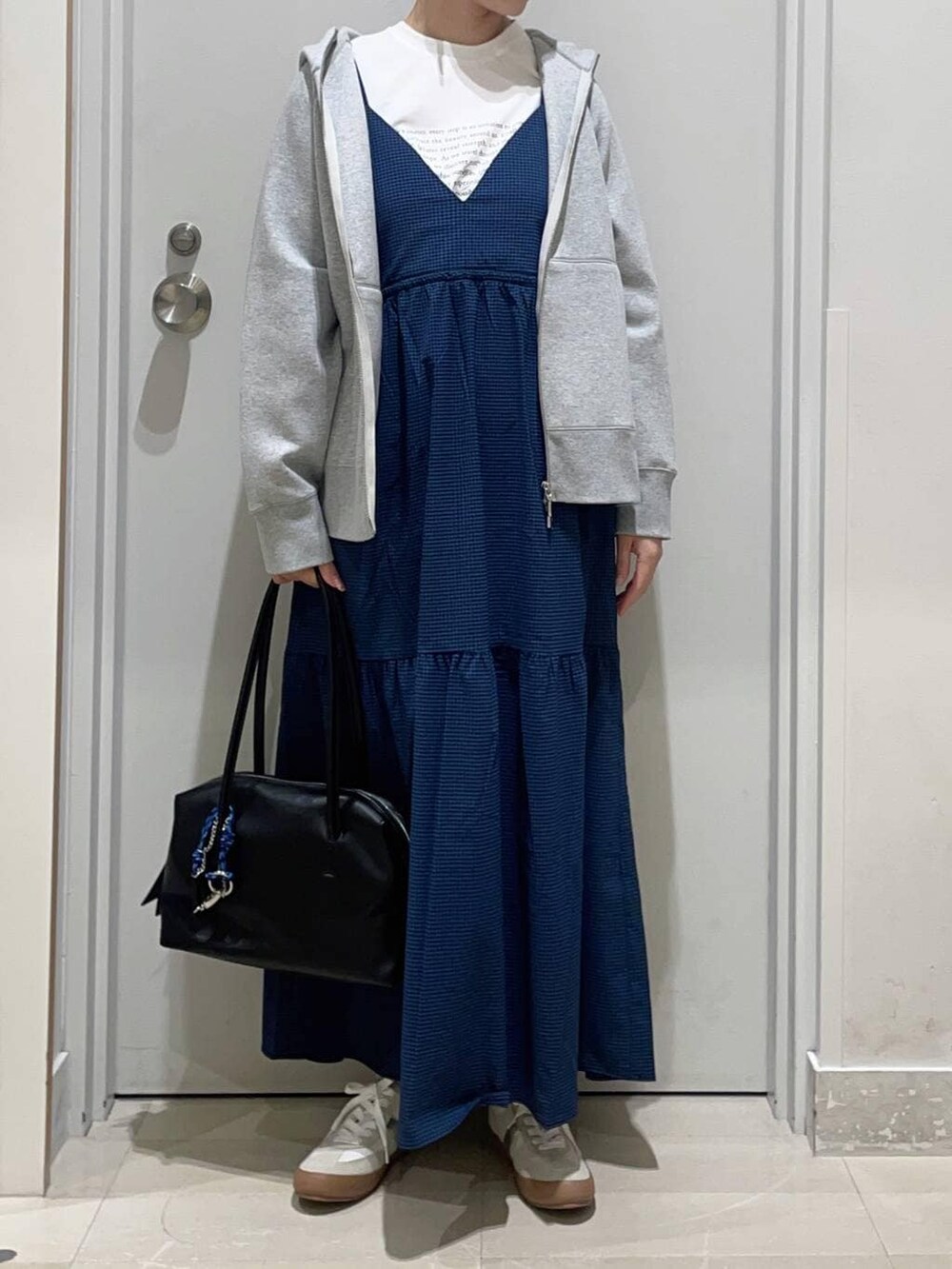 ホワイト系のスニーカー、グレー系のパーカー、ブルー系のワンピースを着用したレディースの春コーディネートの2枚目の写真