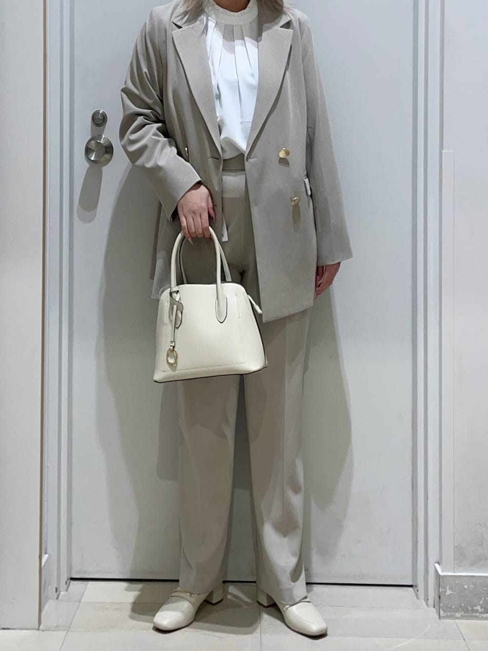 ベージュ系のローファー、ホワイト系のショルダーバッグ、ベージュ系のセットアップを着用したレディースの冬コーディネートの2枚目の写真