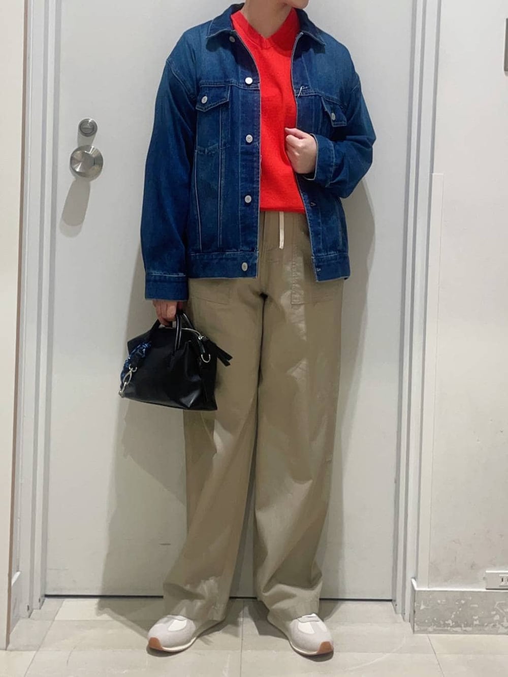 ブルー系のデニムジャケット、レッド系のニット/セーター、ベージュ系のその他パンツを着用したレディースの春コーディネートの2枚目の写真