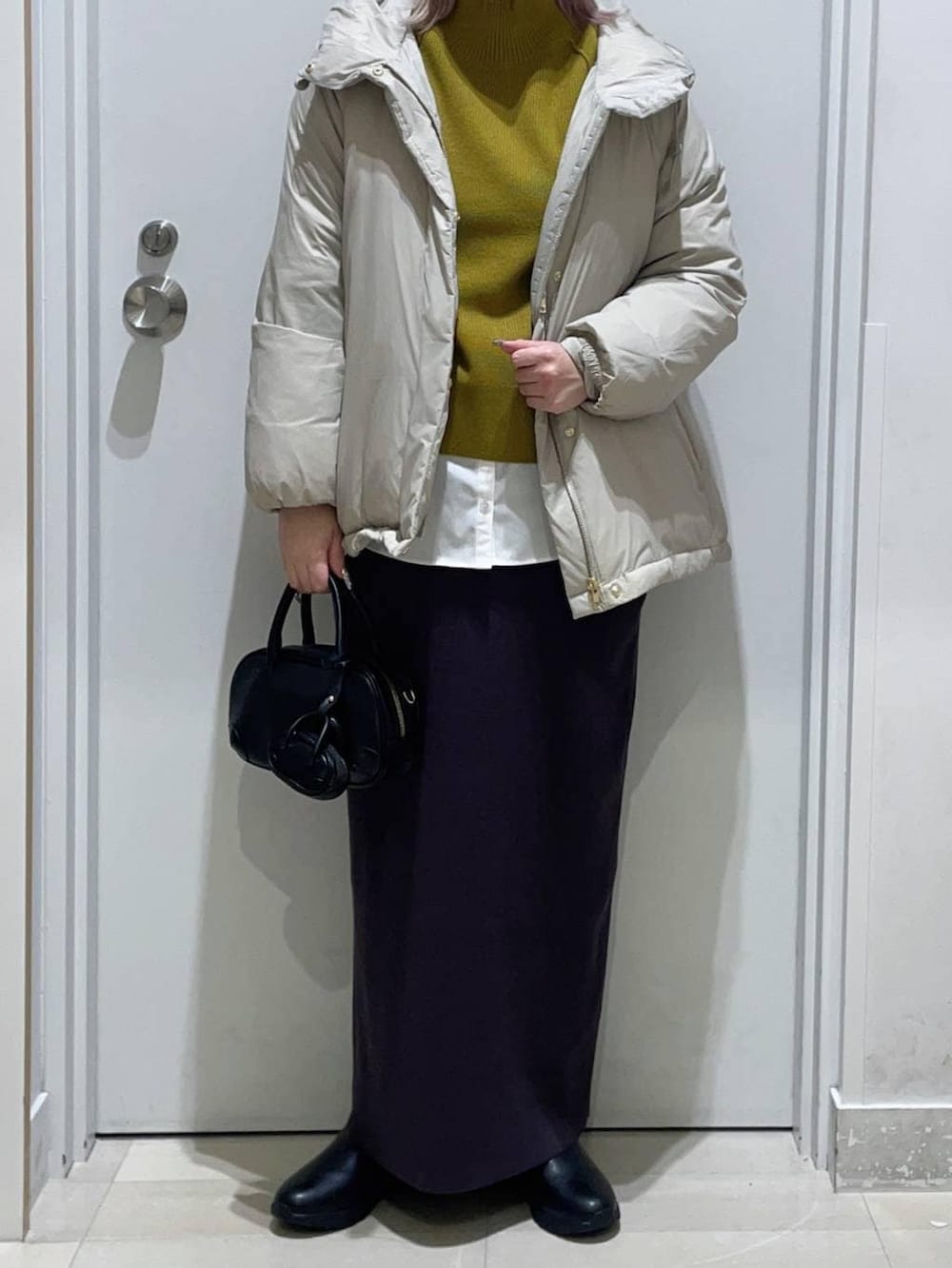 ベージュ系のダウンジャケット/コート、グレー系のワンピース、ホワイト系のTシャツ/カットソーを着用したレディースの冬コーディネートの2枚目の写真