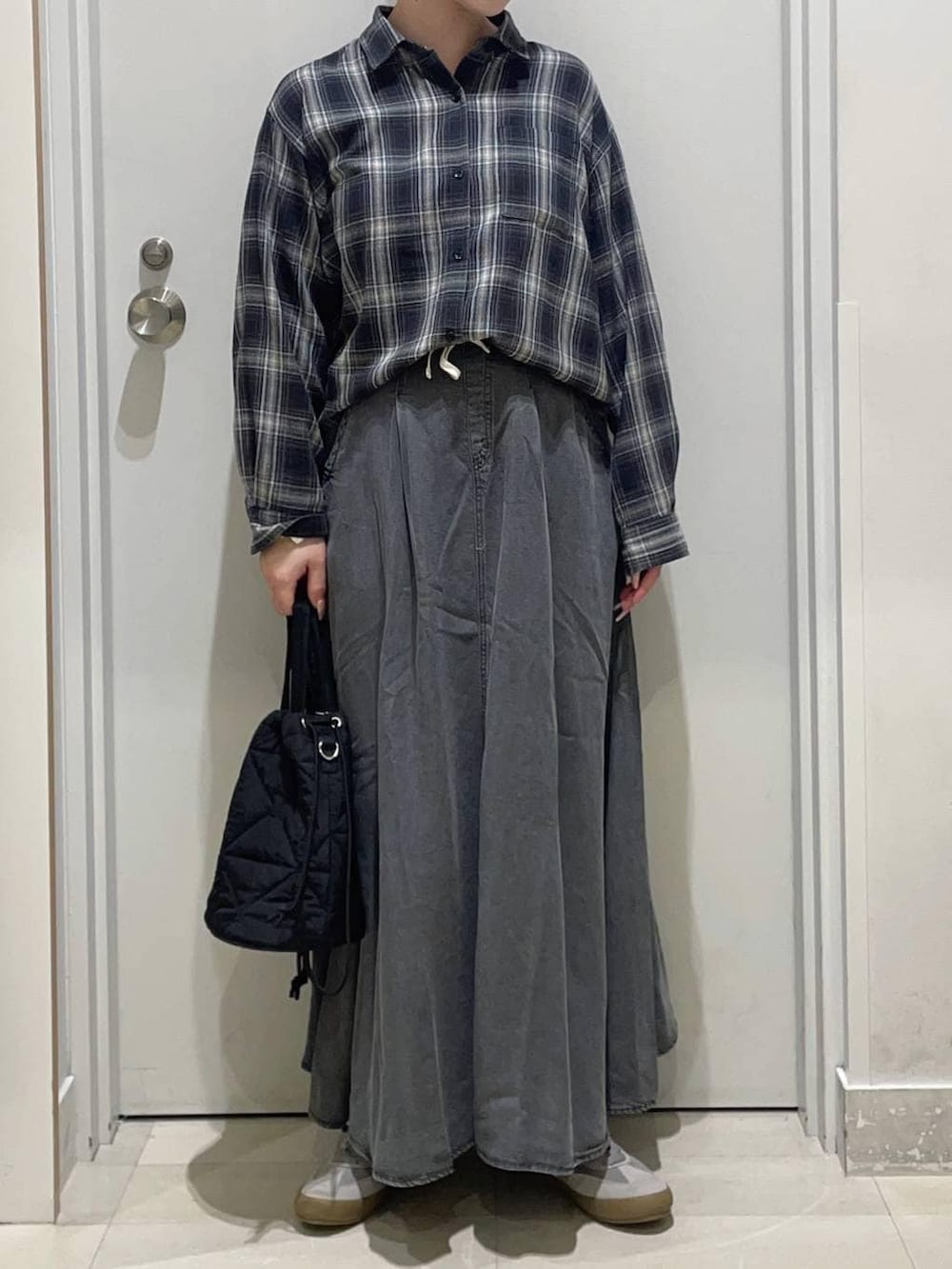 グレー系のスニーカー、ブラック系のハンドバッグ、ブラック系のシャツ/ブラウスを着用したレディースの冬コーディネートの2枚目の写真