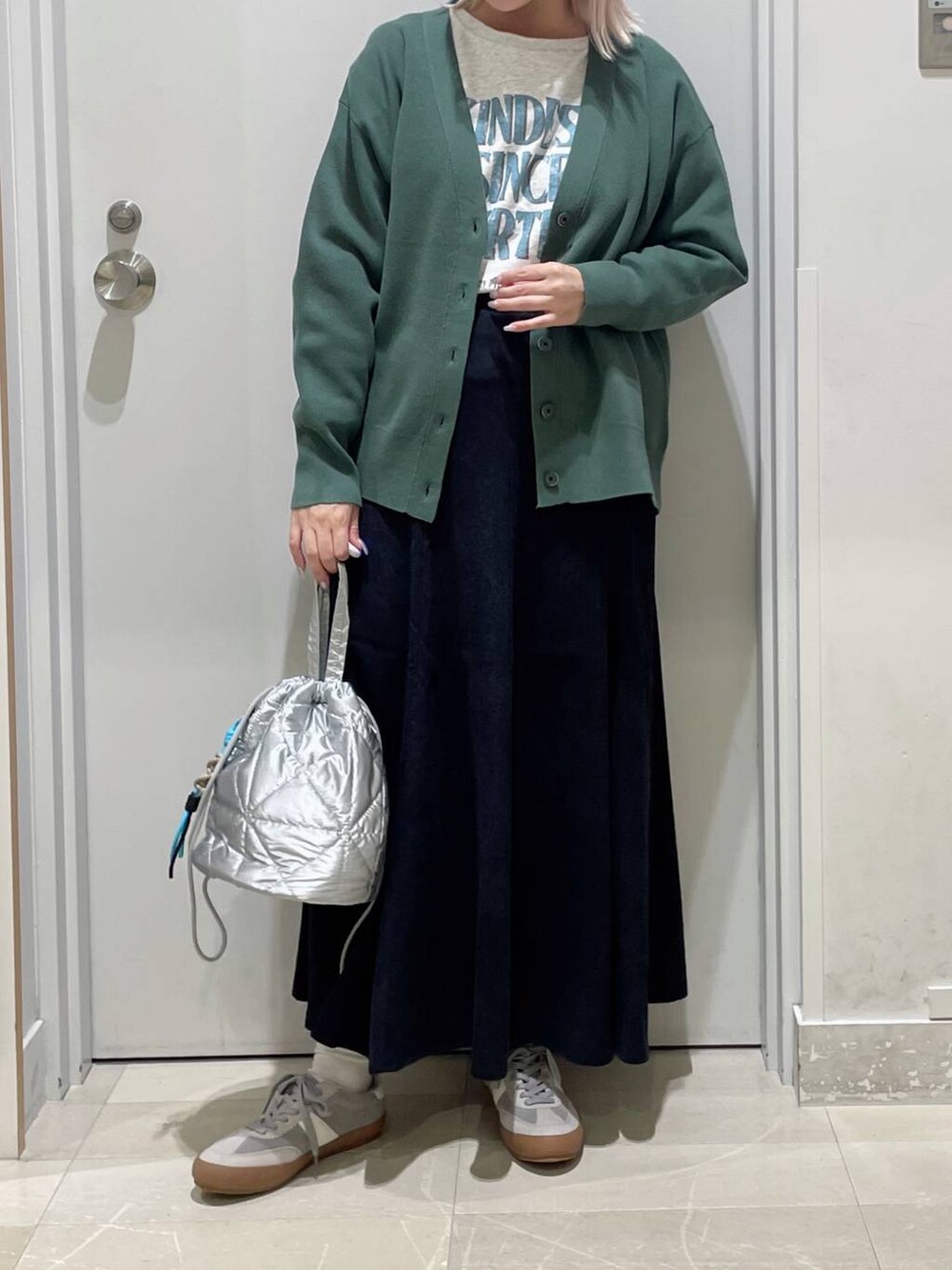 グレー系のスニーカー、グリーン系のカーディガン/ボレロ、グレー系のスカートを着用したレディースの秋コーディネートの2枚目の写真