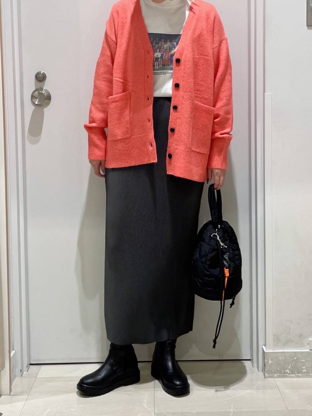 ピンク系のカーディガン/ボレロ、ブラック系のハンドバッグ、ブラック系のブーツを着用したレディースの秋コーディネートの2枚目の写真