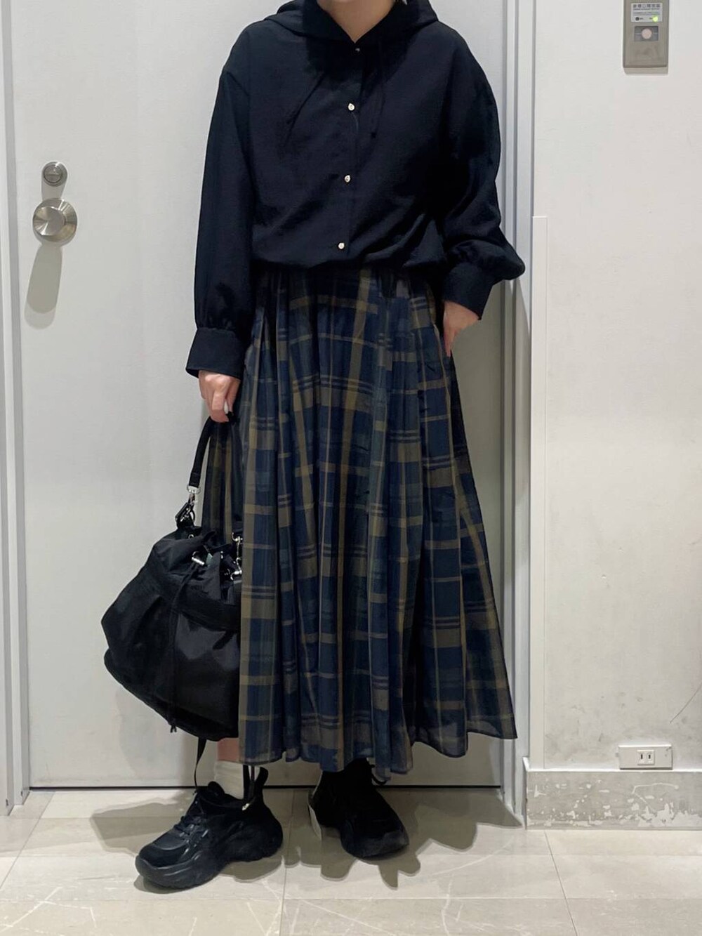 ブラック系のショルダーバッグ、ブラック系のキャミソール、ブルー系のスカートを着用したレディースの秋コーディネートの2枚目の写真