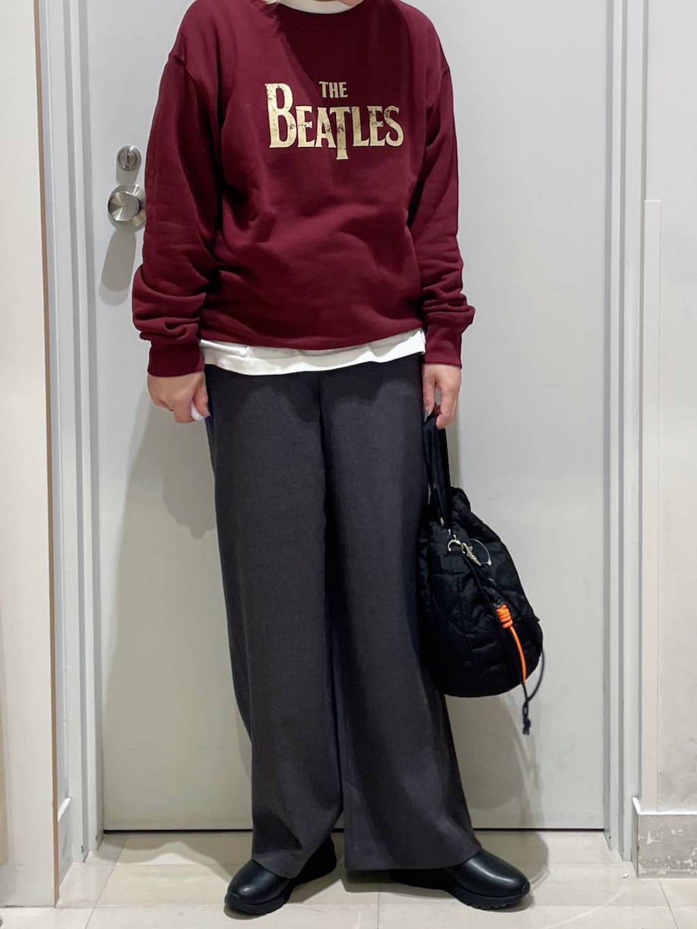 ブラック系のハンドバッグ、ブラック系のブーツ、ホワイト系のTシャツ/カットソーを着用したレディースの秋コーディネートの2枚目の写真