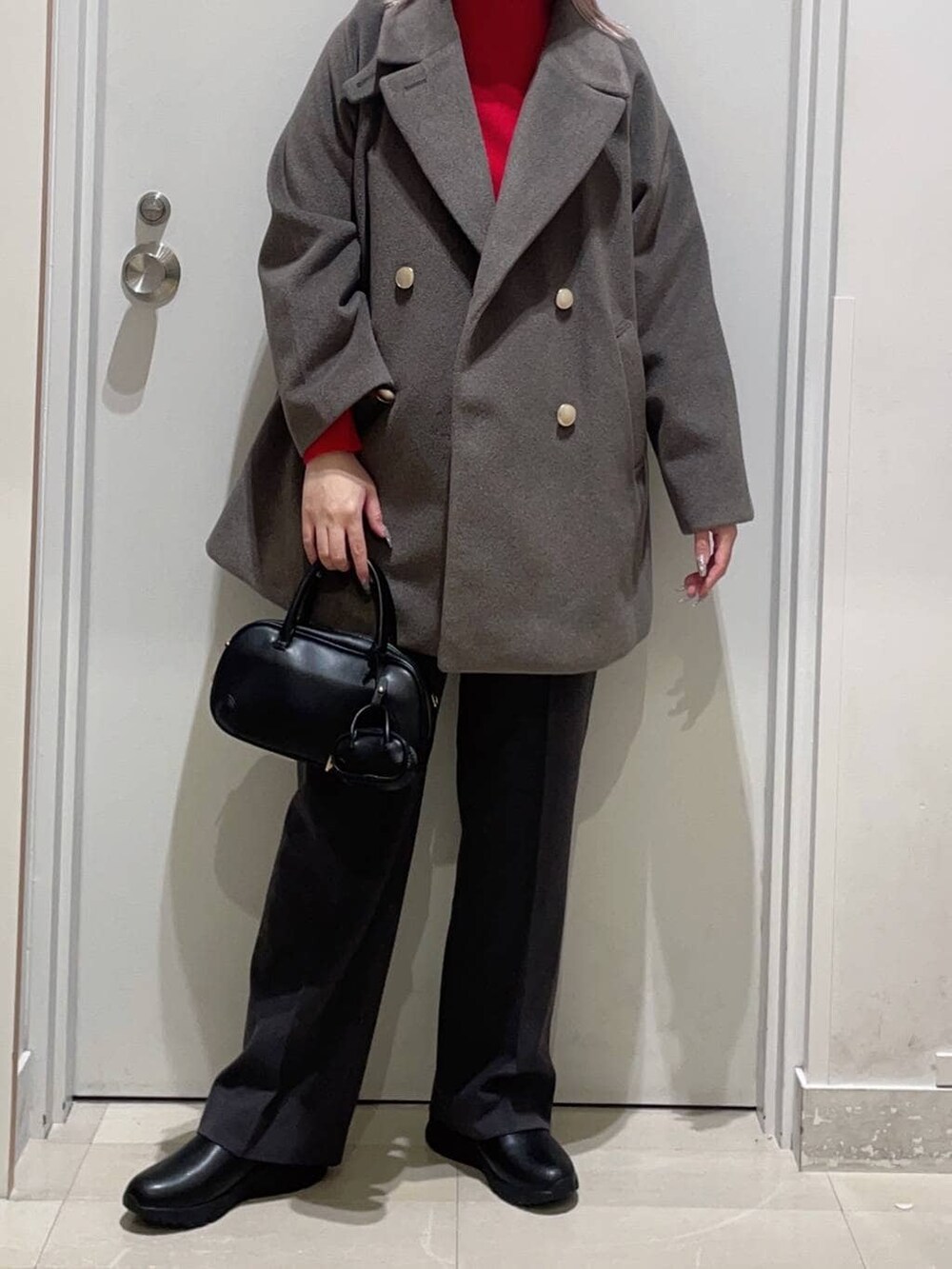 ブラウン系のチェスターコート、ブラック系のブーツ、ブラック系のその他パンツを着用したレディースの冬コーディネートの2枚目の写真