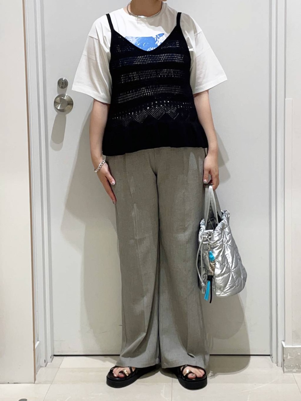 シルバー系のハンドバッグ、ベージュ系のその他パンツ、ホワイト系のTシャツ/カットソーを着用したレディースの夏コーディネートの2枚目の写真