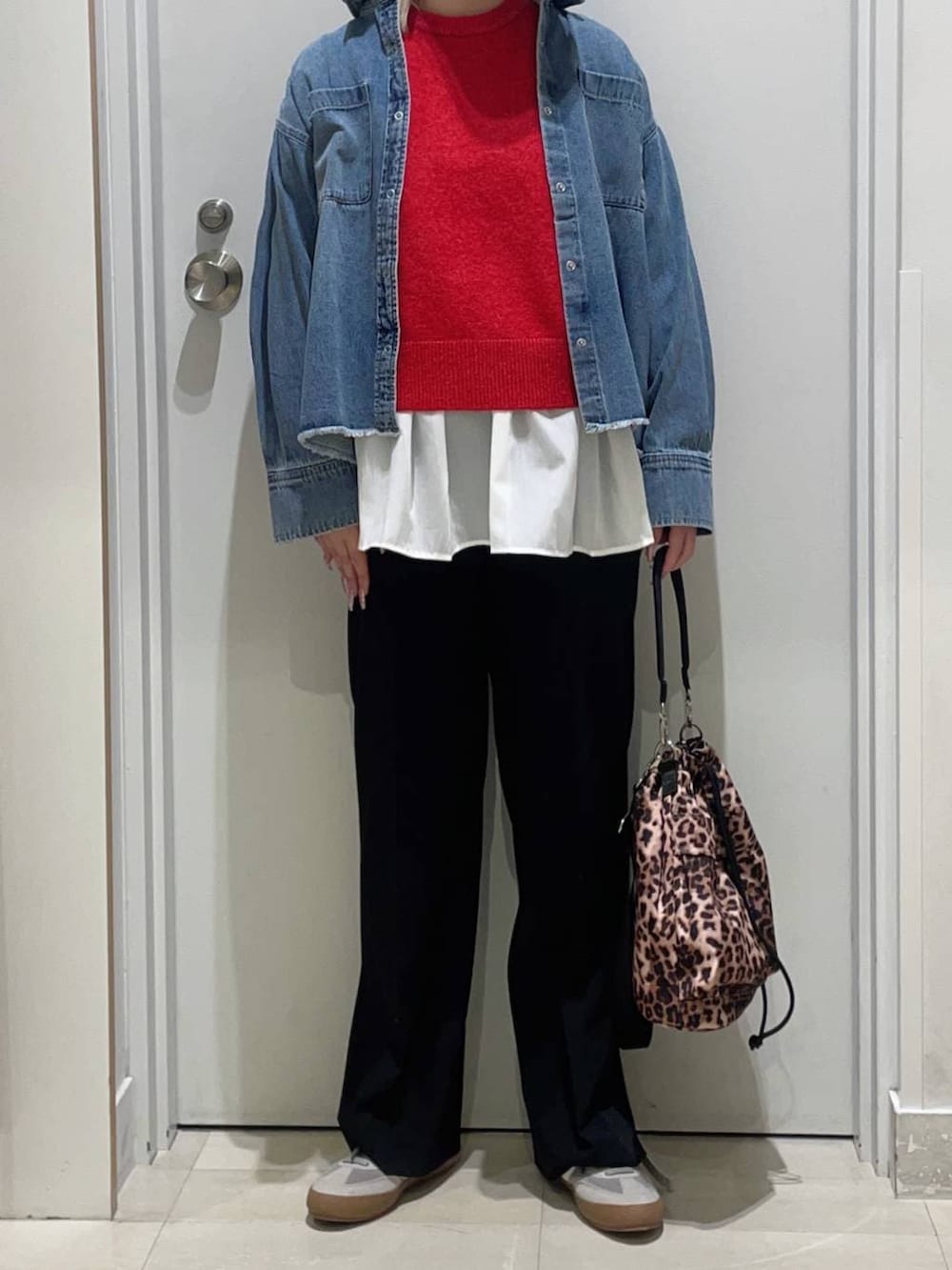 グレー系のスニーカー、レッド系のニット/セーター、ホワイト系のTシャツ/カットソーを着用したレディースの冬コーディネートの2枚目の写真