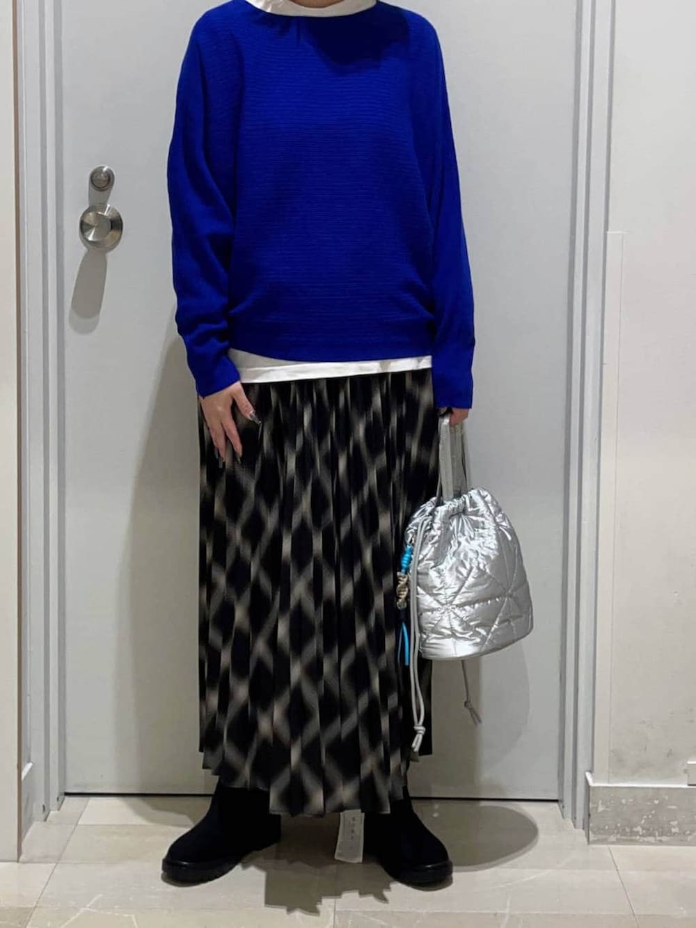 ホワイト系のTシャツ/カットソー、ブラック系のブーツ、ブラック系のスカートを着用したレディースの秋コーディネートの2枚目の写真