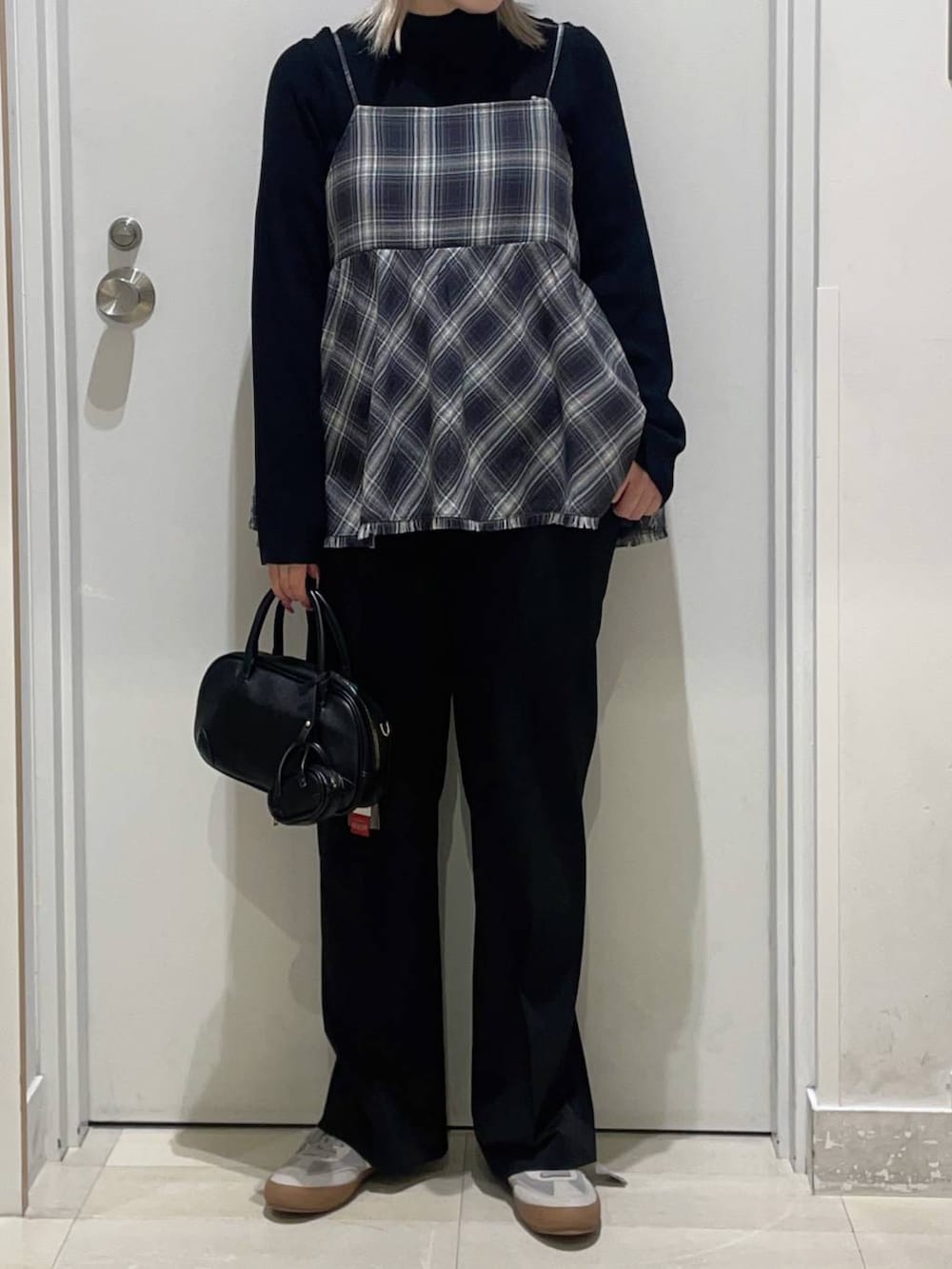 グレー系のスニーカー、ブラック系のニット/セーター、ブルー系のスラックスを着用したレディースの冬コーディネートの2枚目の写真