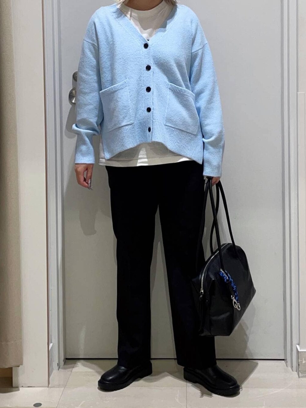 ブラック系のボストンバッグ、ブルー系のカーディガン/ボレロ、ブラック系のその他パンツを着用したレディースの秋コーディネートの2枚目の写真