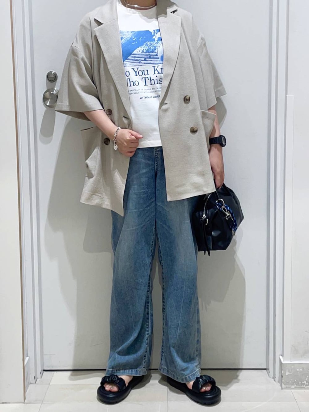 ベージュ系のテーラードジャケット、ブルー系のデニムパンツ、ホワイト系のTシャツ/カットソーを着用したレディースの夏コーディネートの2枚目の写真