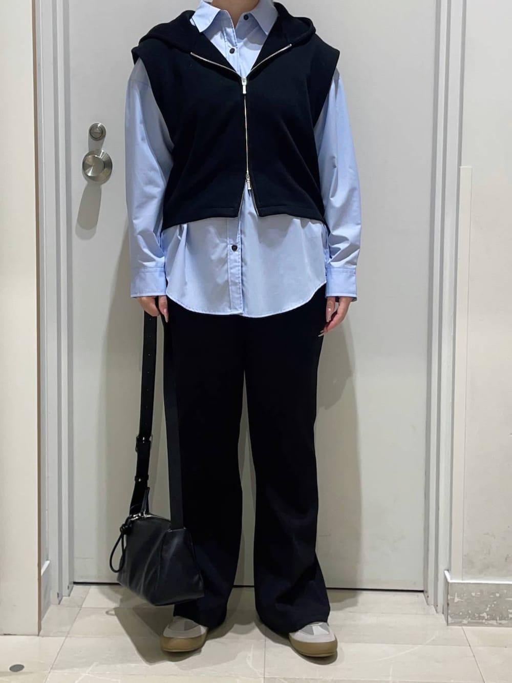 グレー系のスニーカー、ブルー系のシャツ/ブラウス、ブラック系のスラックスを着用したレディースの春コーディネートの2枚目の写真