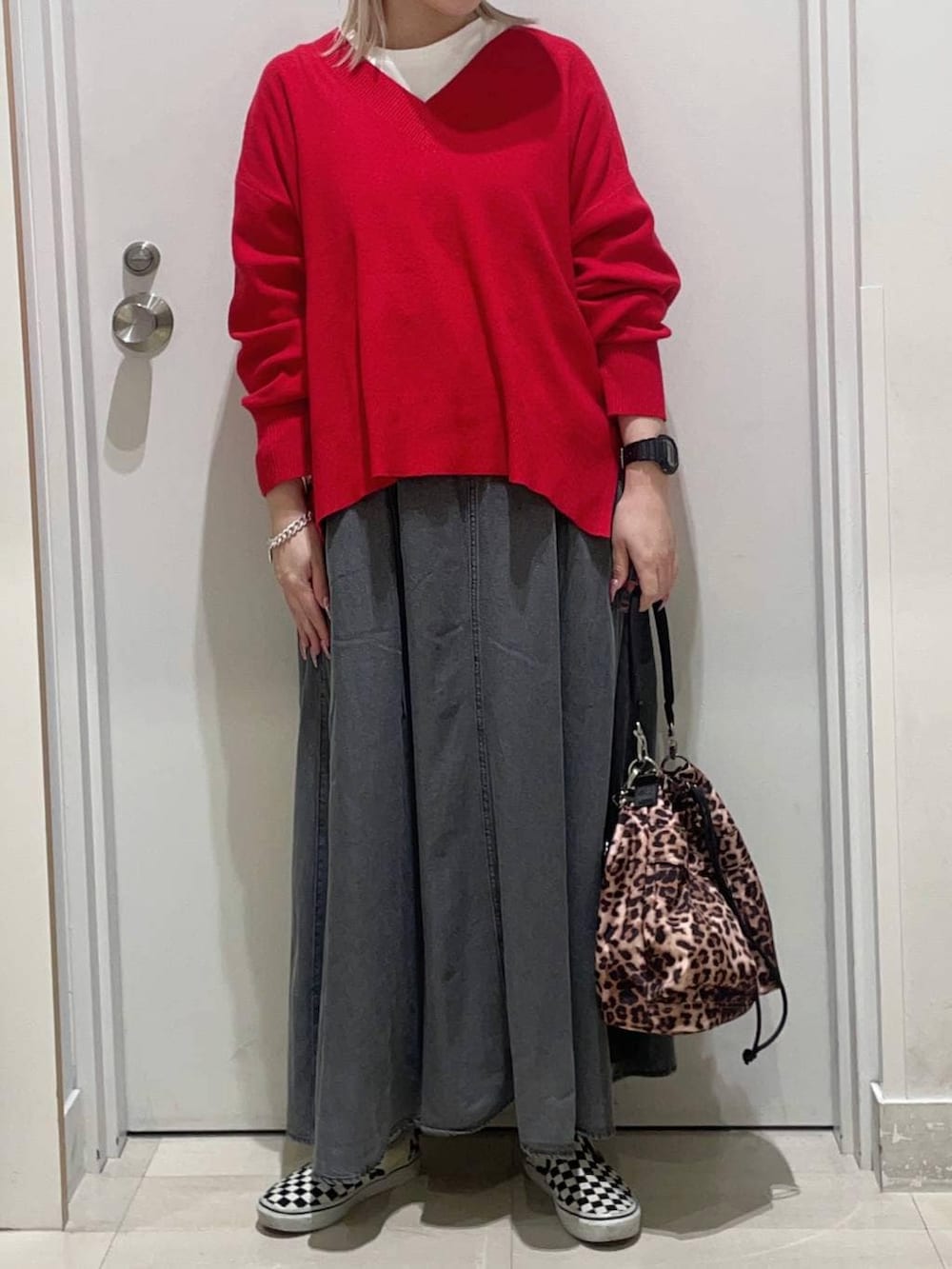 レッド系のニット/セーター、ブラック系のデニムスカート、ホワイト系のTシャツ/カットソーを着用したレディースの冬コーディネートの2枚目の写真