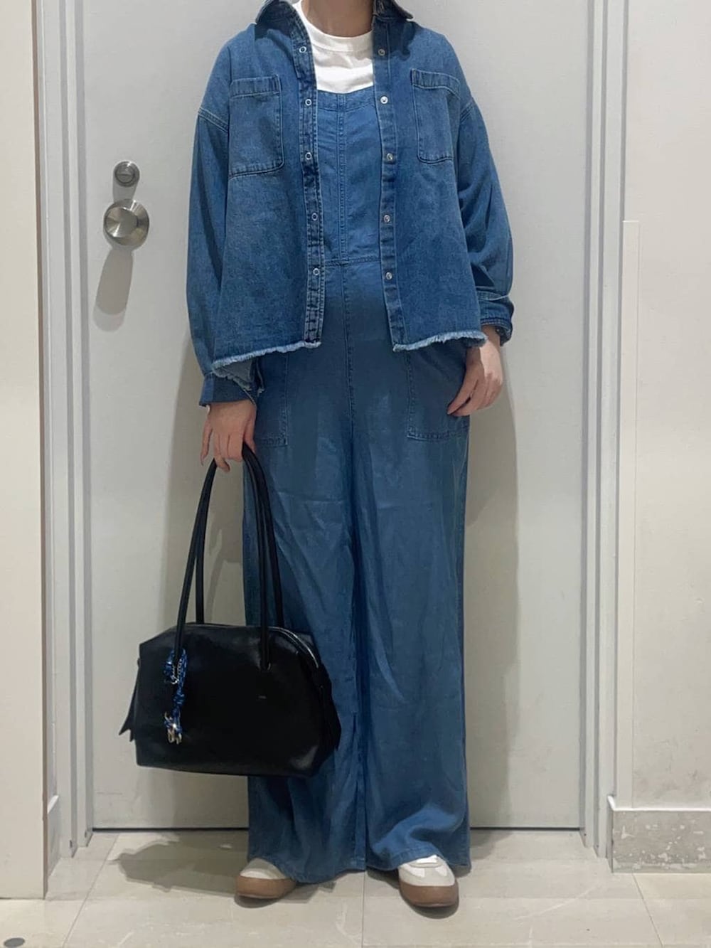 ホワイト系のスニーカー、ブルー系のシャツ/ブラウス、ホワイト系のTシャツ/カットソーを着用したレディースの春コーディネートの2枚目の写真