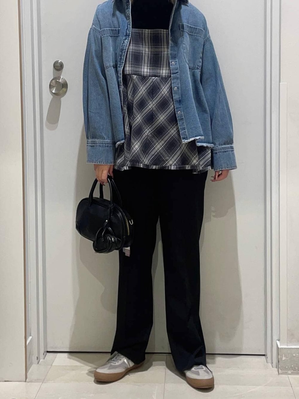 グレー系のスニーカー、ブラック系のニット/セーター、ブルー系のスラックスを着用したレディースの冬コーディネートの2枚目の写真