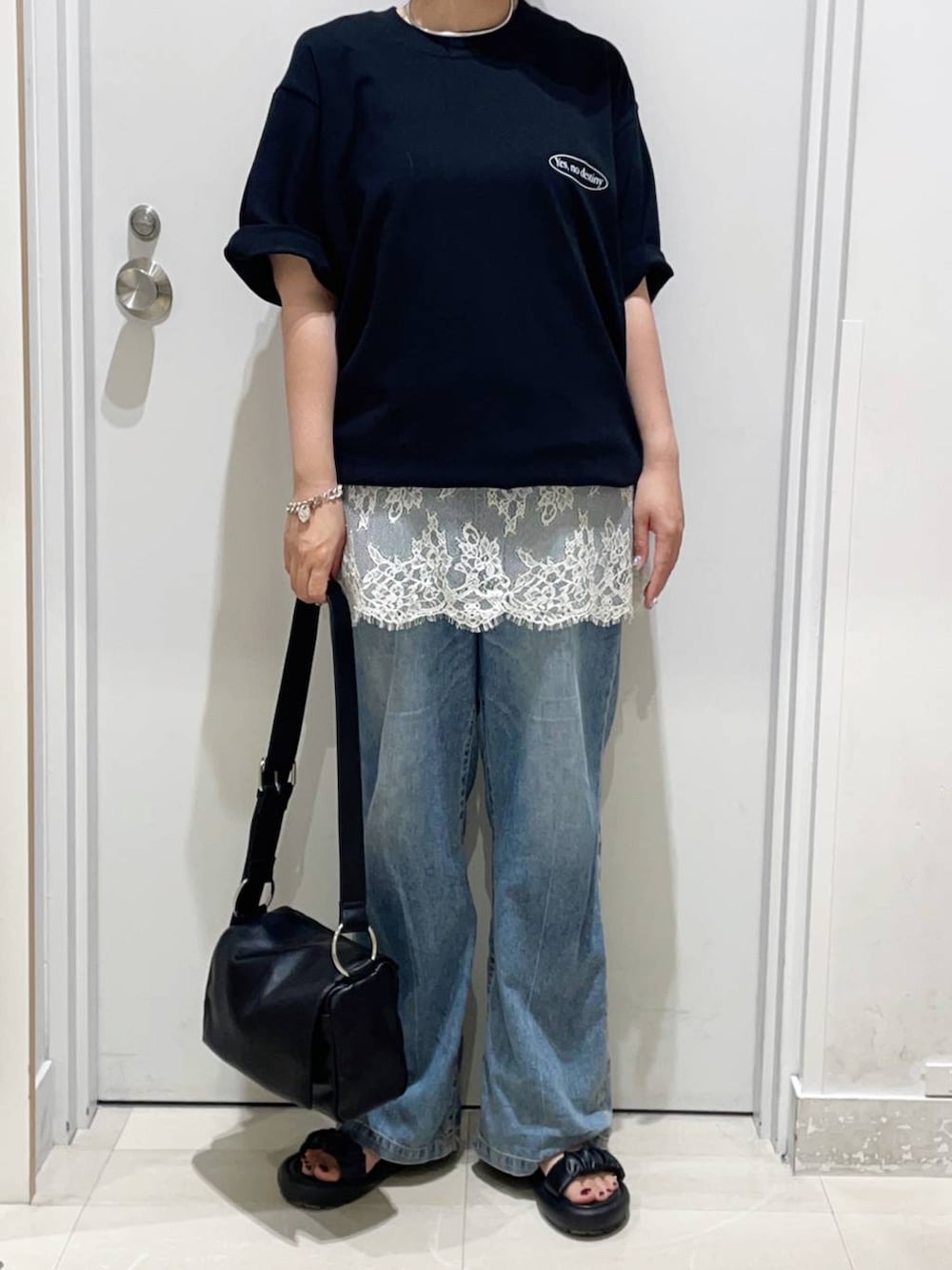ブルー系のデニムパンツ、ホワイト系のキャミソール、ブラック系のサンダルを着用したレディースの夏コーディネートの2枚目の写真