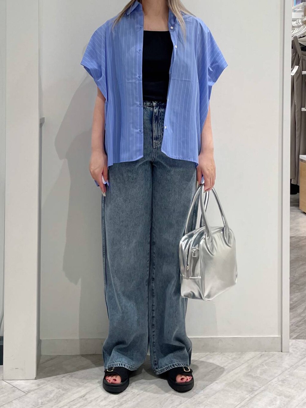 ブルー系のデニムパンツ、グレー系のボストンバッグ、ブラック系のタンクトップを着用したレディースの夏コーディネートの2枚目の写真