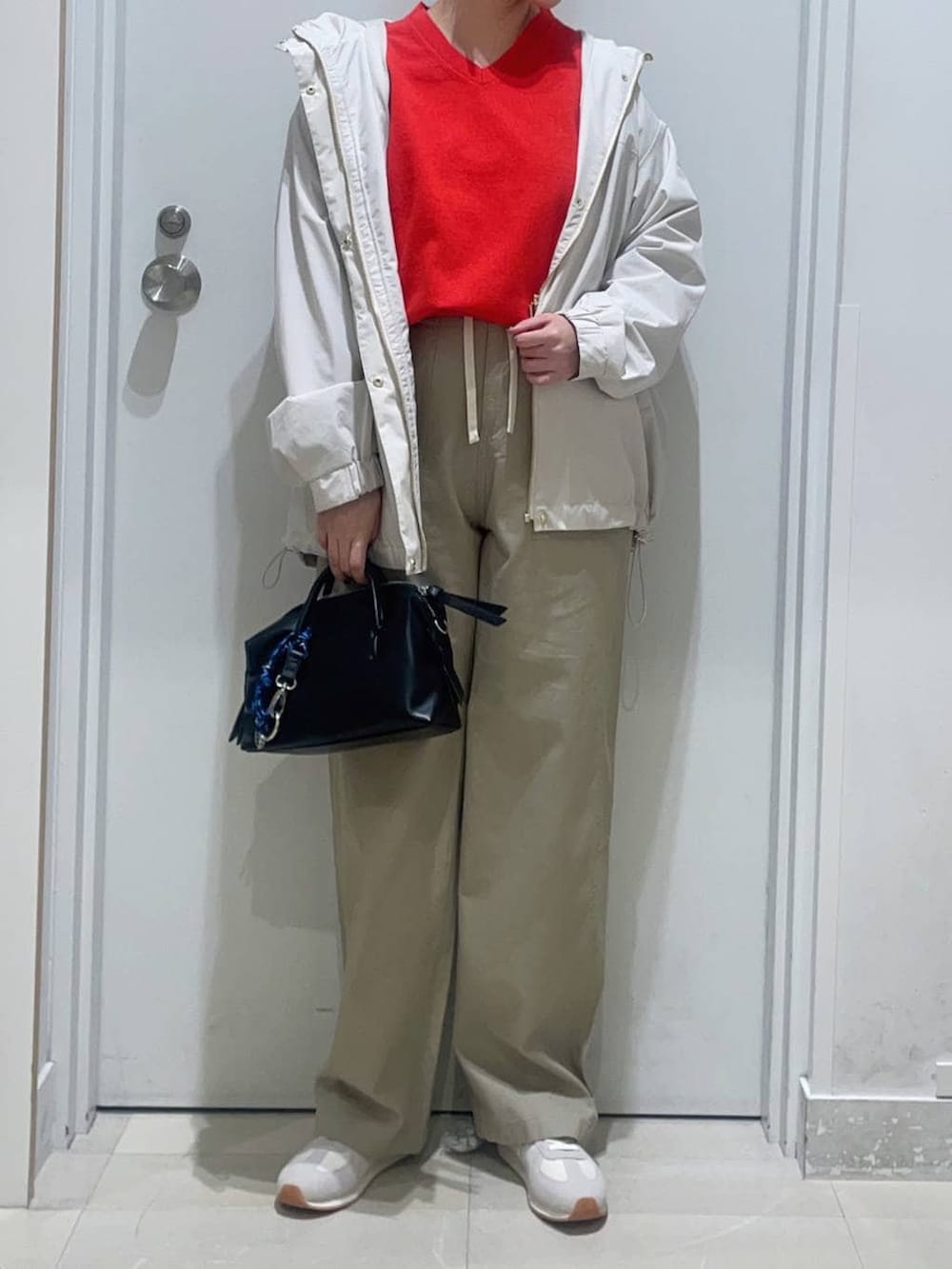 ベージュ系のスニーカー、ベージュ系のマウンテンパーカー、レッド系のニット/セーターを着用したレディースの春コーディネートの2枚目の写真