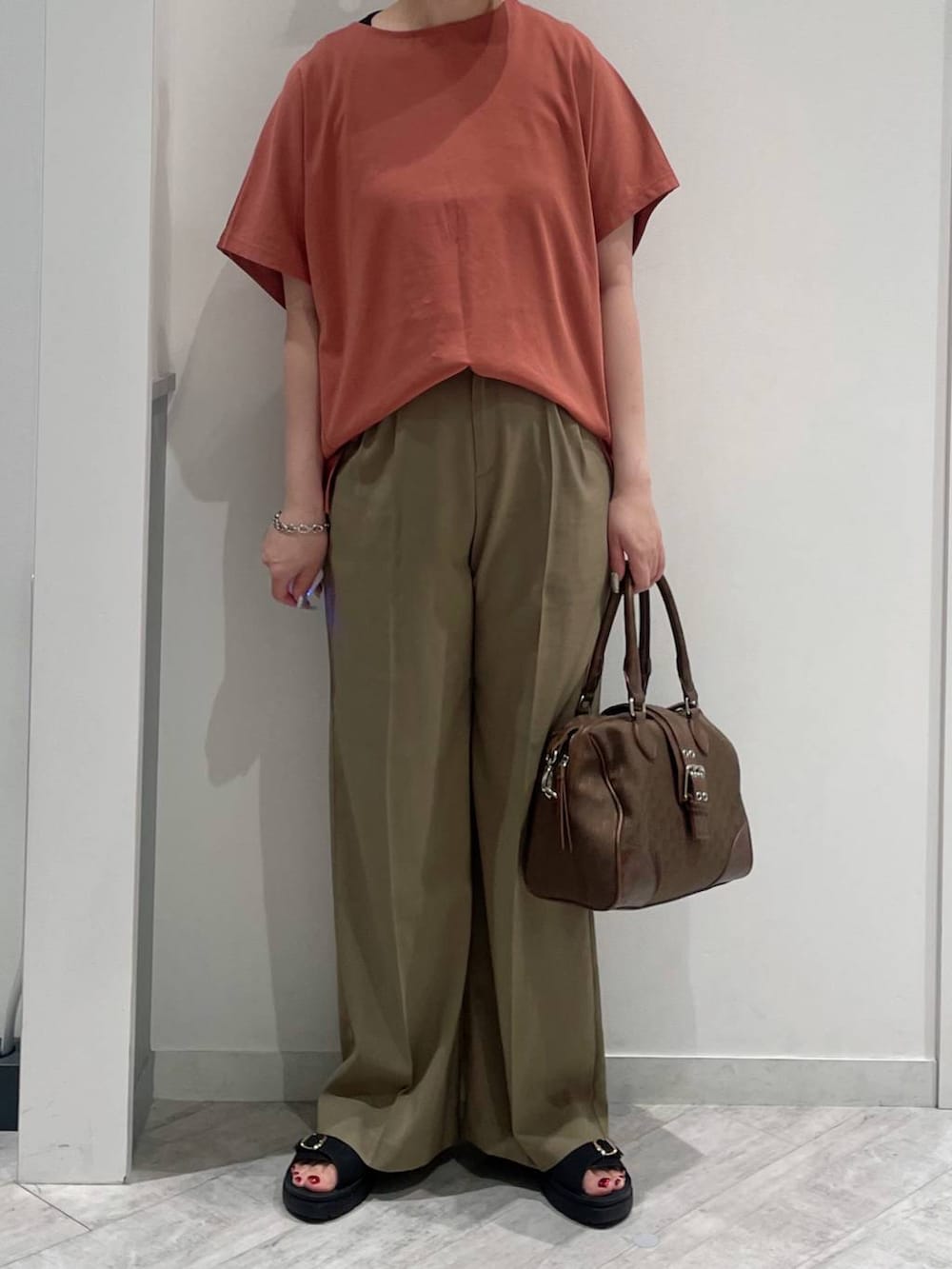 グリーン系のボストンバッグ、ブラウン系のTシャツ/カットソー、ブラック系のサンダルを着用したレディースの春コーディネートの2枚目の写真