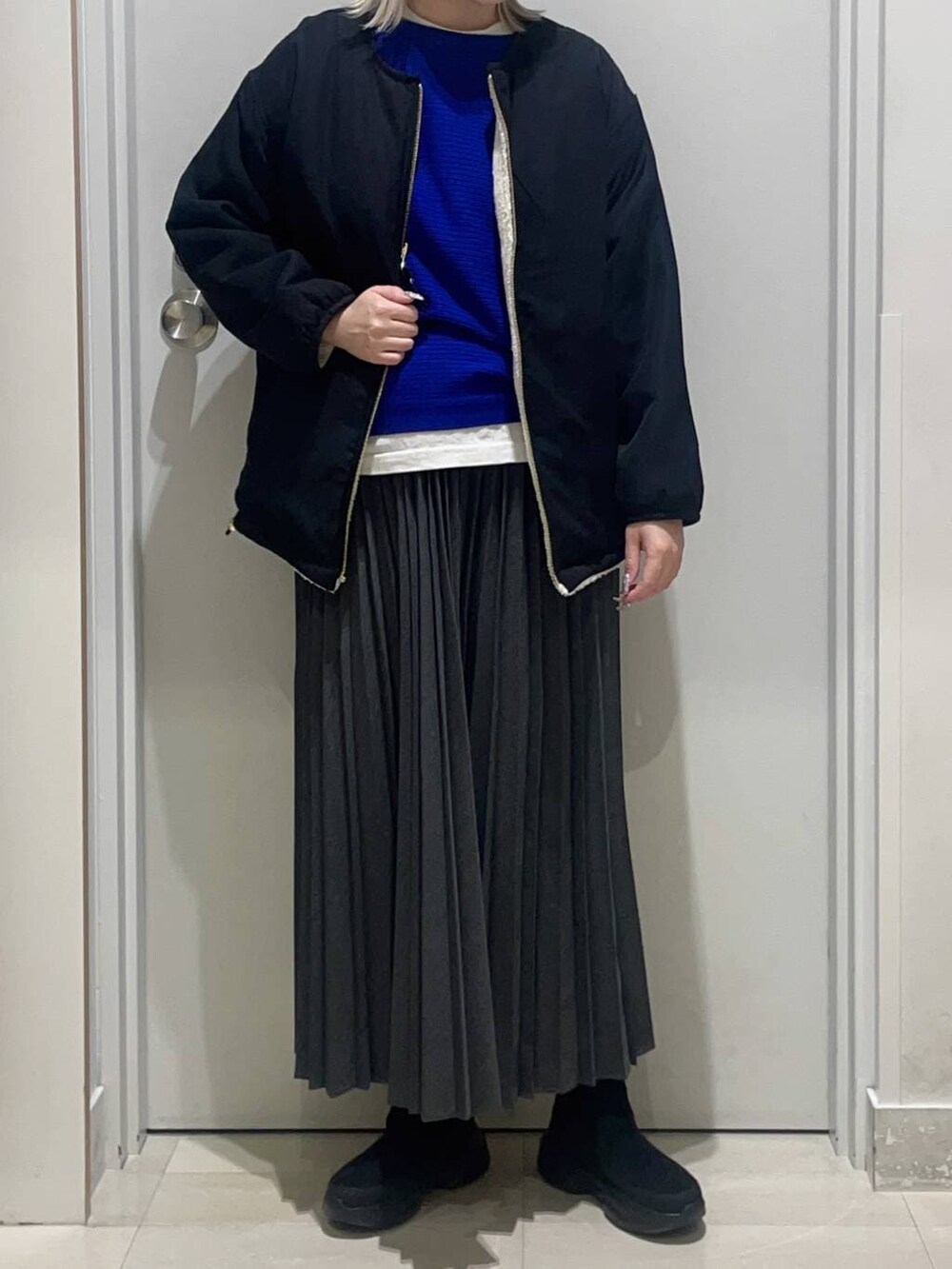 ホワイト系のブルゾン、ホワイト系のTシャツ/カットソー、ブラック系のブーツを着用したレディースの冬コーディネートの2枚目の写真