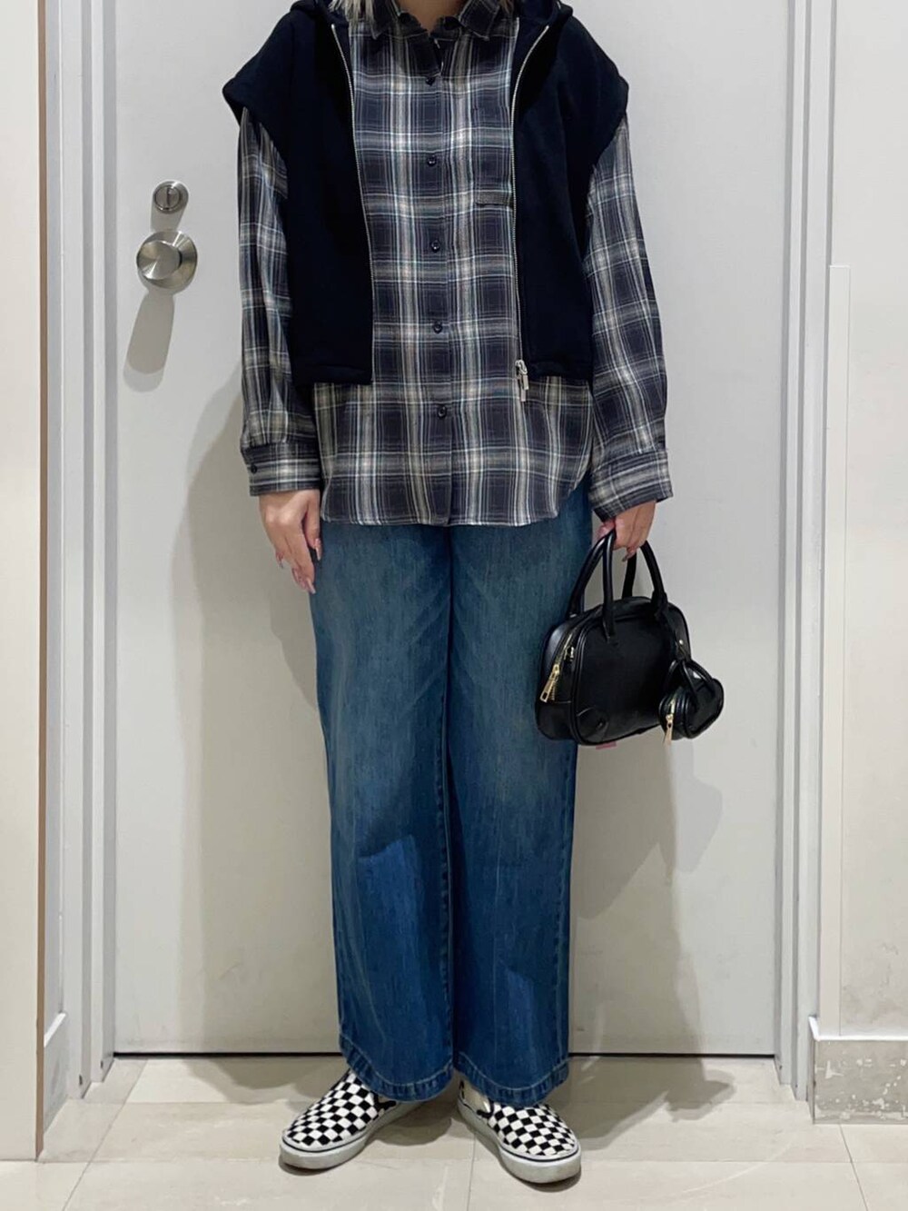 ブラック系のハンドバッグ、ブルー系のデニムパンツ、ブラック系のシャツ/ブラウスを着用したレディースの冬コーディネートの2枚目の写真