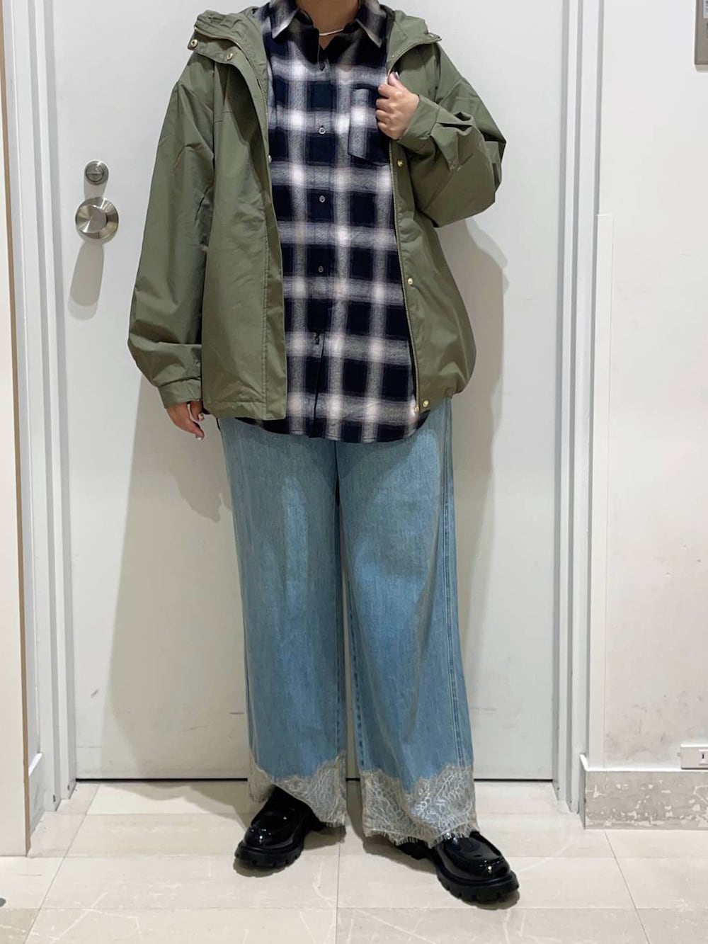 グリーン系のマウンテンパーカー、ブルー系のデニムパンツ、ブラック系のシャツ/ブラウスを着用したレディースの秋コーディネートの2枚目の写真