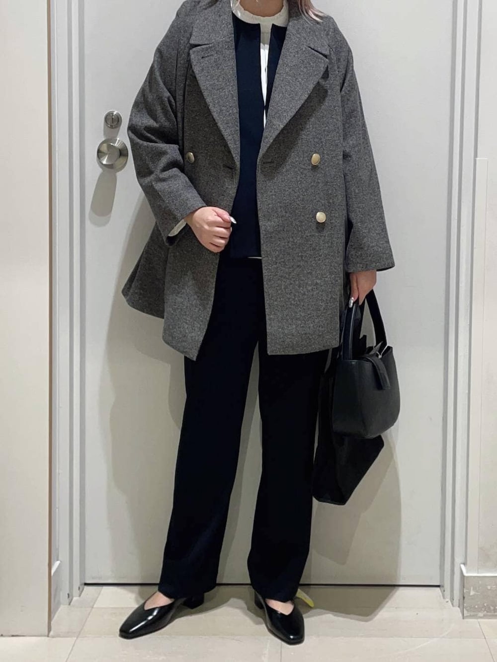 グレー系のチェスターコート、ブラック系のパンプス、ブルー系のセットアップを着用したレディースの冬コーディネートの2枚目の写真