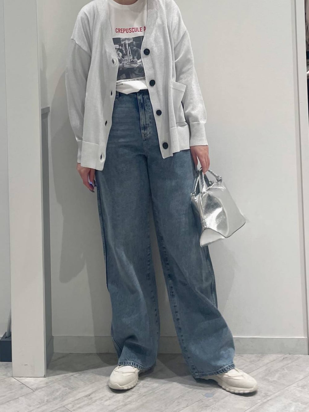 シルバー系のショルダーバッグ、ホワイト系のTシャツ/カットソー、ブルー系のデニムパンツを着用したレディースの春コーディネートの2枚目の写真