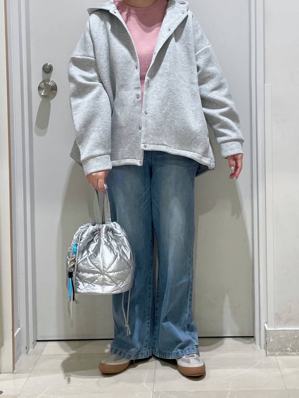 グレー系のスニーカー、ピンク系のニット/セーター、ブルー系のデニムパンツを着用したレディースの秋コーディネートの2枚目の写真