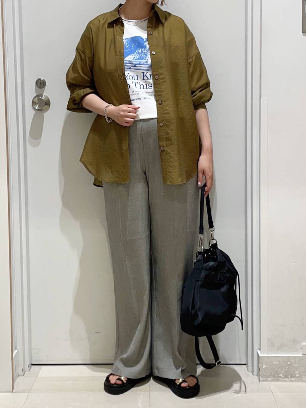 ブラック系のショルダーバッグ、ベージュ系のその他パンツ、ホワイト系のTシャツ/カットソーを着用したレディースの夏コーディネートの2枚目の写真
