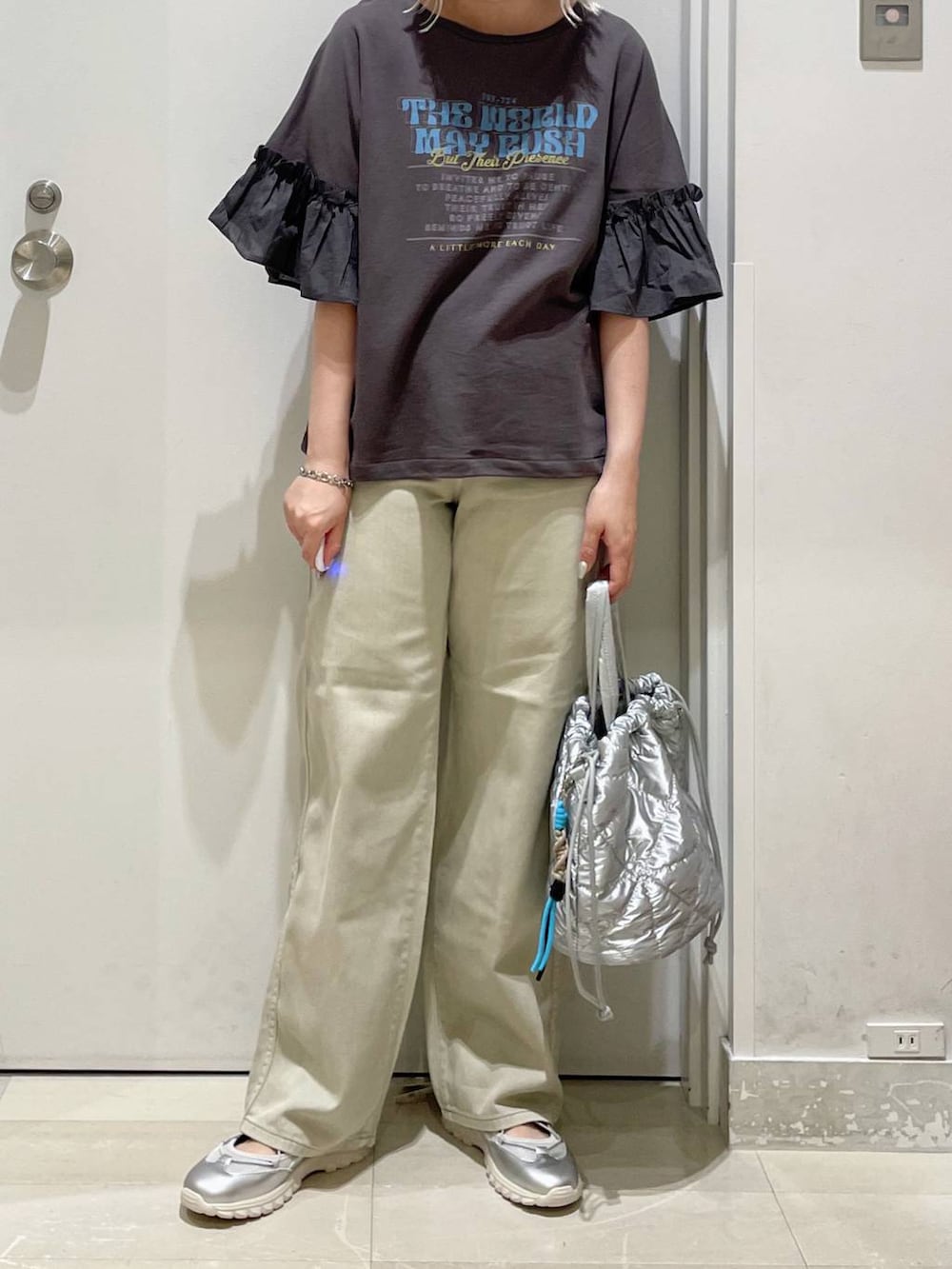 グレー系のスニーカー、ベージュ系のデニムパンツ、シルバー系のハンドバッグを着用したレディースの秋コーディネートの2枚目の写真